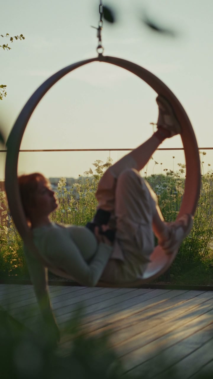 Person Relaxing in Rooftop Swing Chair at Sunset