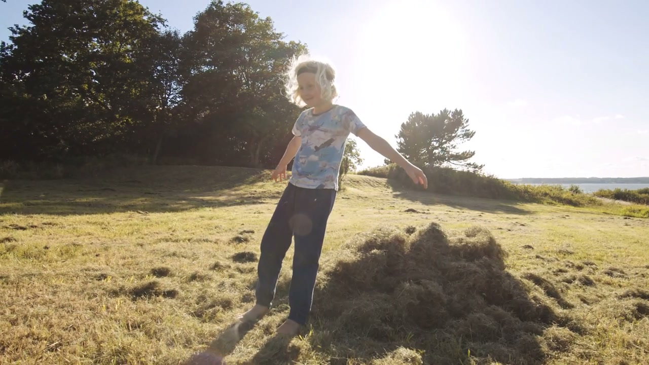 Carefree Boy Falling into Grass Pile