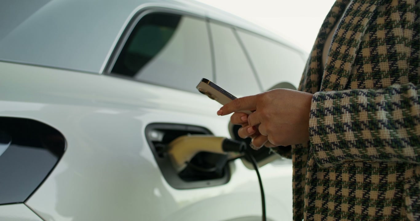Hands Using Phone While EV Charges