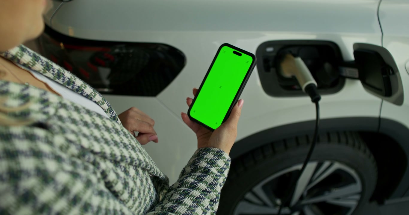 Green Screen Phone Next to Charging Electric Vehicle