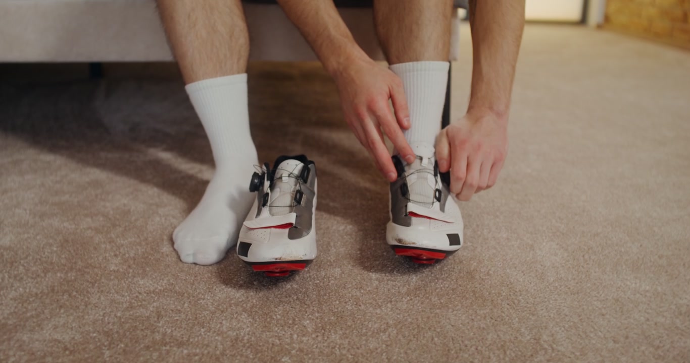 Person Donning And Adjusting Cycling Shoes