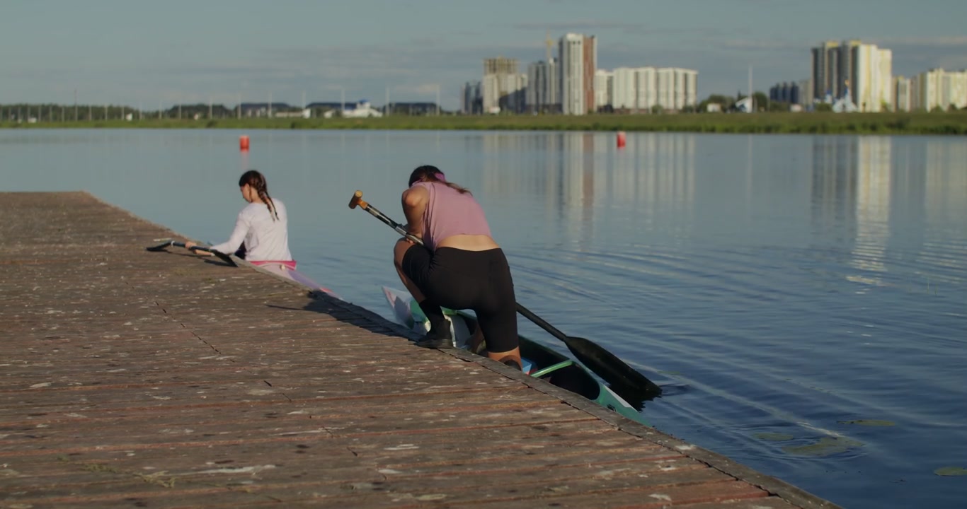 Paddlers Entering Kayaks from Dock on Lake